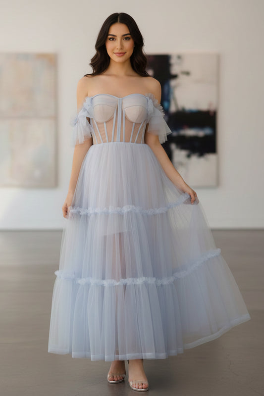 Sevoba light blue tea-length tulle prom dress featuring a sheer corset bodice with visible boning and tiered ruffle skirt, front view in gallery setting