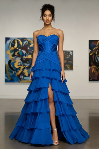 Woman in strapless royal blue ruffled evening gown with high slit, standing in art gallery