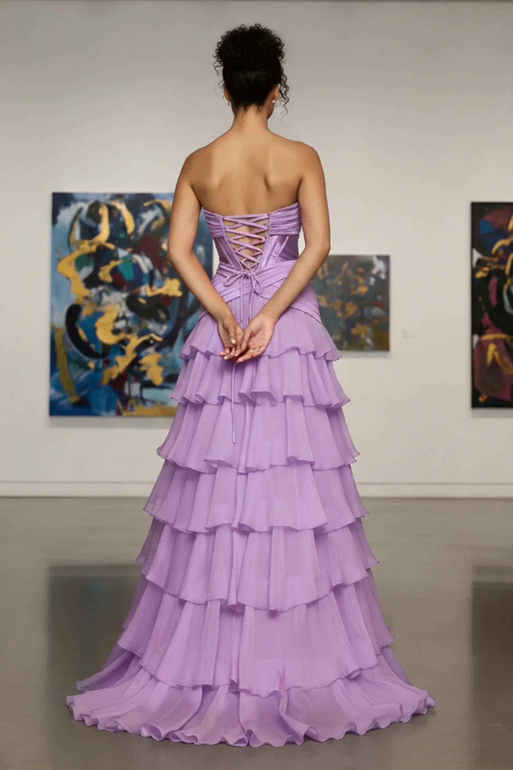 Back view of woman in lilac ruffled strapless evening gown with lace-up corset detail