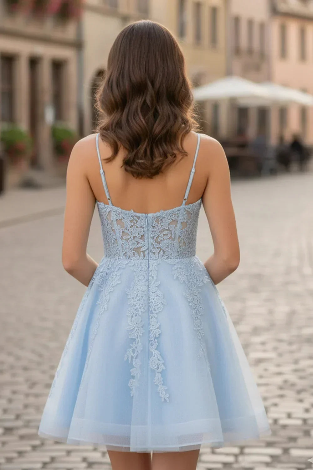 Back view of a woman in a light blue A-line spaghetti strap lace homecoming dress outdoors