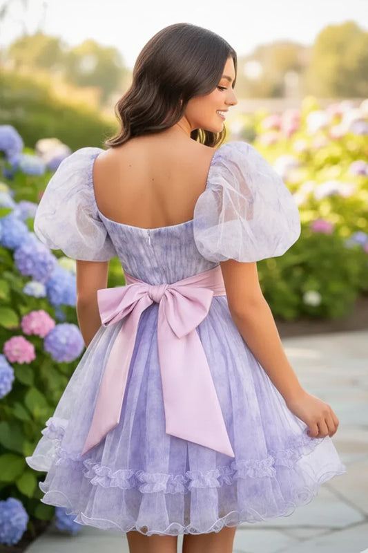 Lilac A-line short homecoming dress with puff sleeves and pink bow, outdoor garden setting