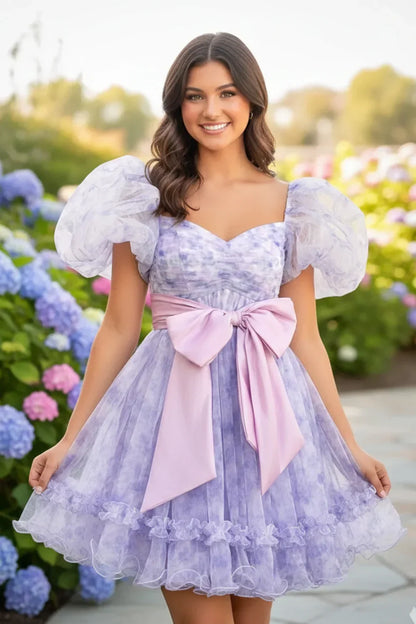 Lavender A-line homecoming dress with sweetheart neckline, puff sleeves, and pink bow, outdoors.