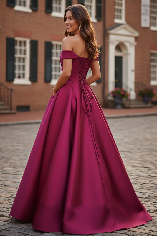 Back view of Sevoba berry pink satin evening gown showing a lace-up corset back and voluminous floor-length skirt, outdoor brick building background