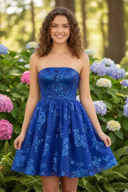 Woman in a blue sequin strapless A-line homecoming dress standing outdoors among hydrangeas.