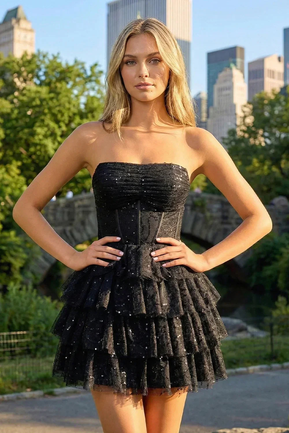 Woman in strapless black tiered sequin homecoming dress outdoors in city park