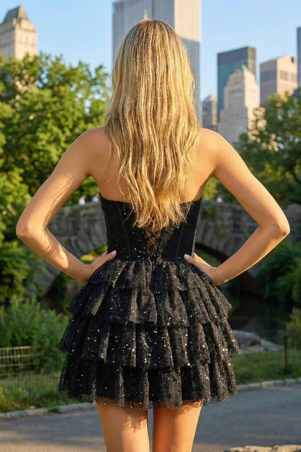 Woman in black strapless tiered sequin homecoming dress outdoors with city skyline