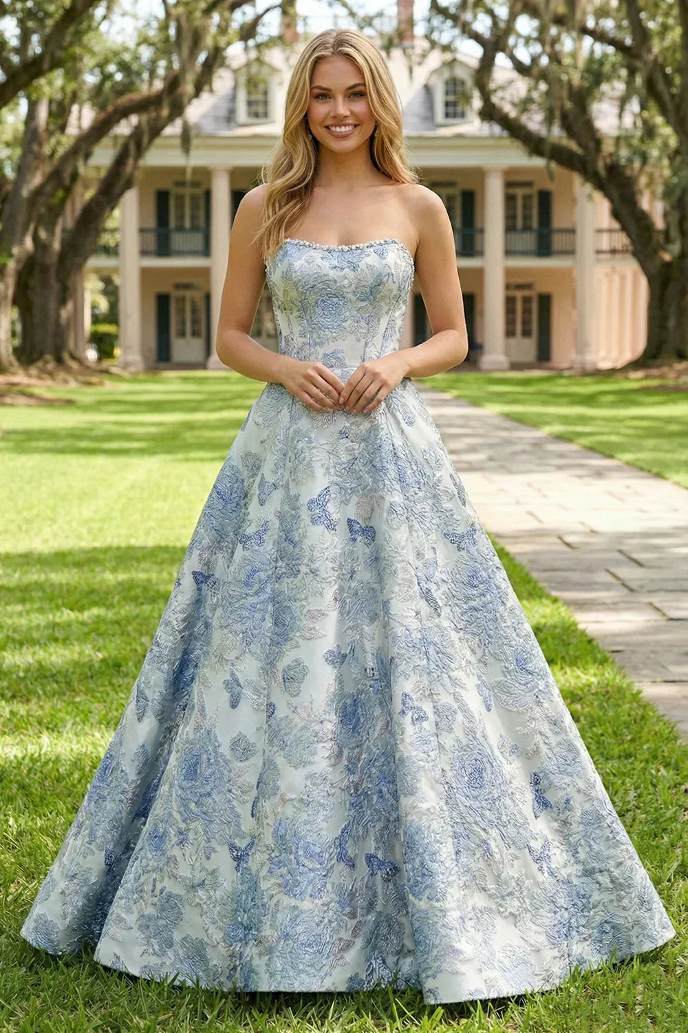 A-line strapless long prom dress in light blue jacquard fabric with floral pattern, worn outdoors.