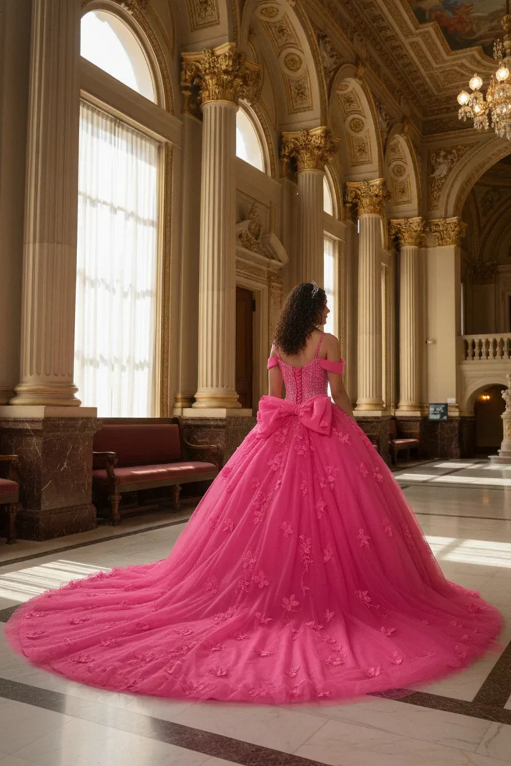 Woman in elegant pink ball gown with 3D floral details and bow in grand hall