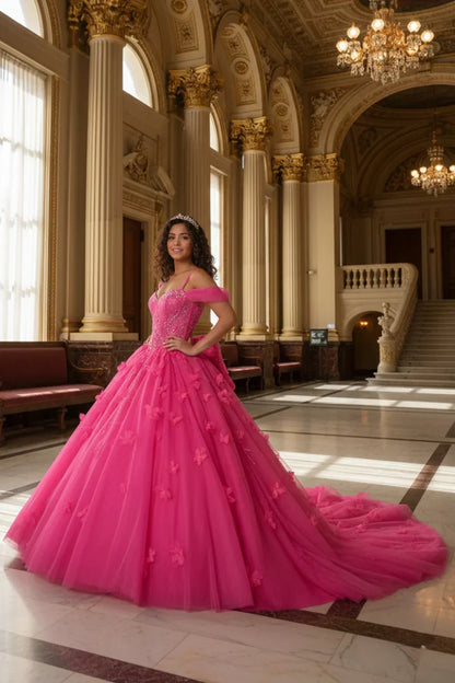 Young woman in a vibrant pink ball gown with 3D floral details, posing in an elegant, grand hall with chandeliers and ornate columns.