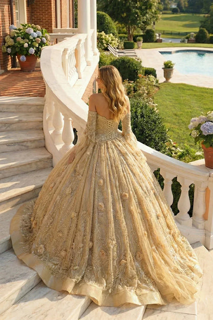 Woman in elegant off-the-shoulder gold tulle ball gown with floral details on marble stairs