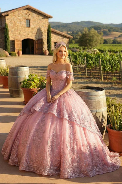 Woman in a pink floral appliqué off-shoulder ball gown dress outdoors by vineyard.
