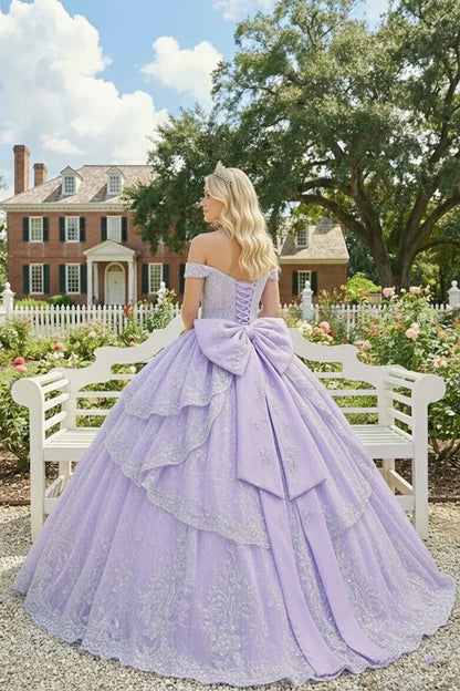 Woman in a lavender ball gown with floral embroidery and large bow outdoors