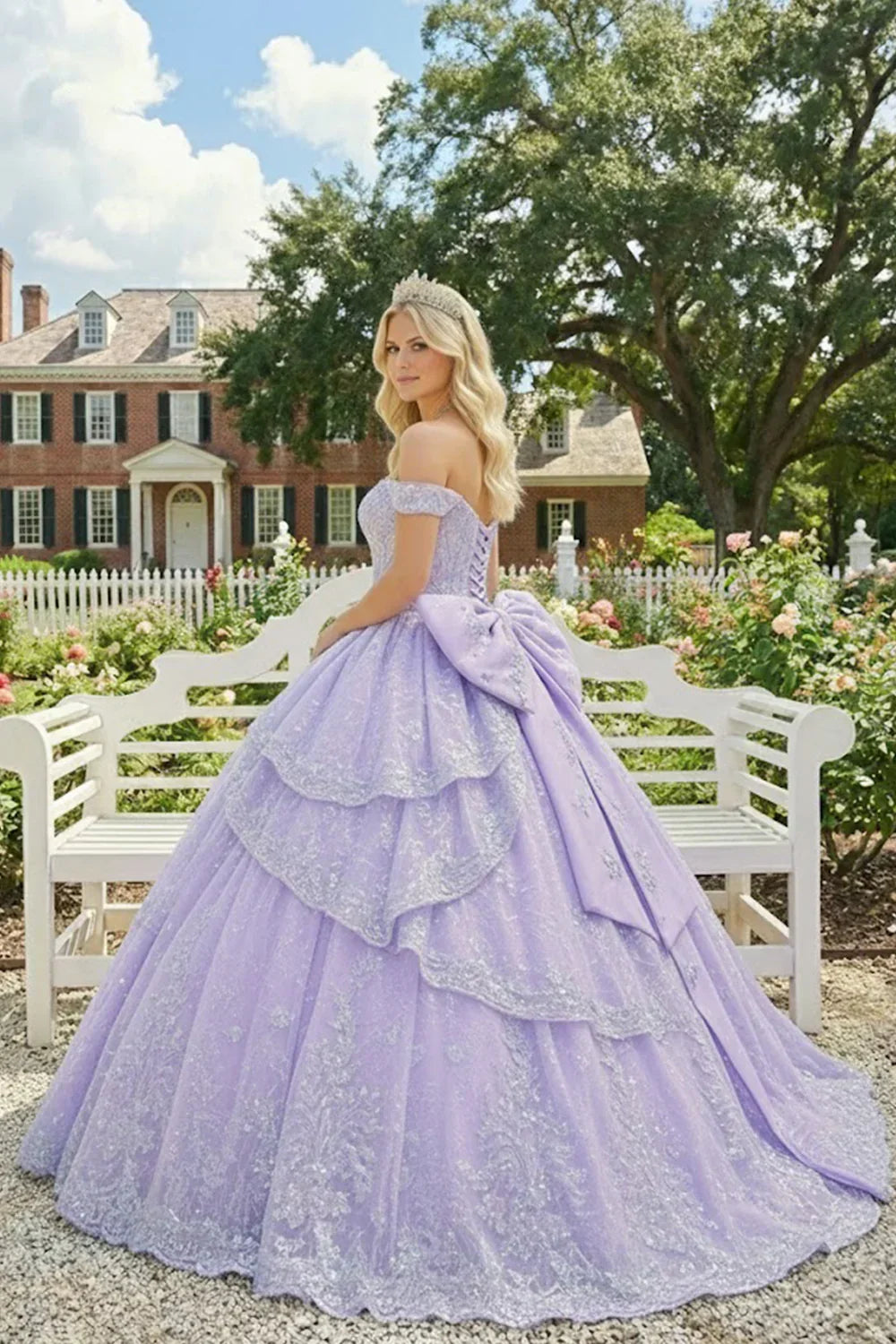 Woman in a lilac off-the-shoulder ball gown with floral embroidery and tiara, outdoor garden setting