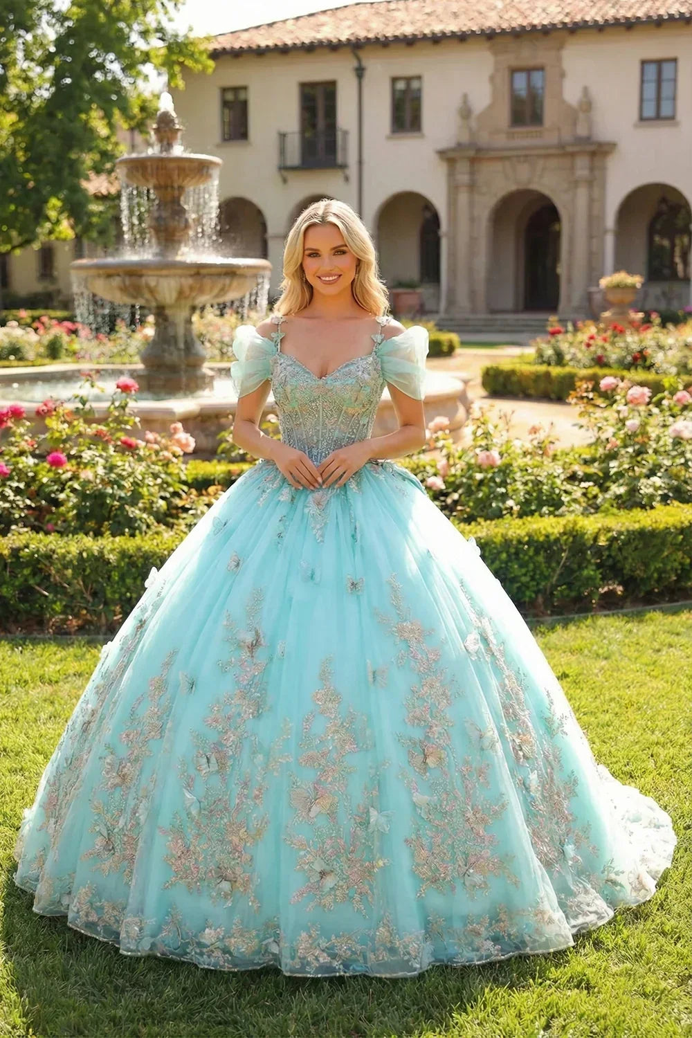 Woman in blue ball gown with floral embroidery and 3D butterfly details outdoors