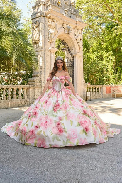 Woman in a floral ball gown with cold shoulder sleeves and tiara standing outdoors