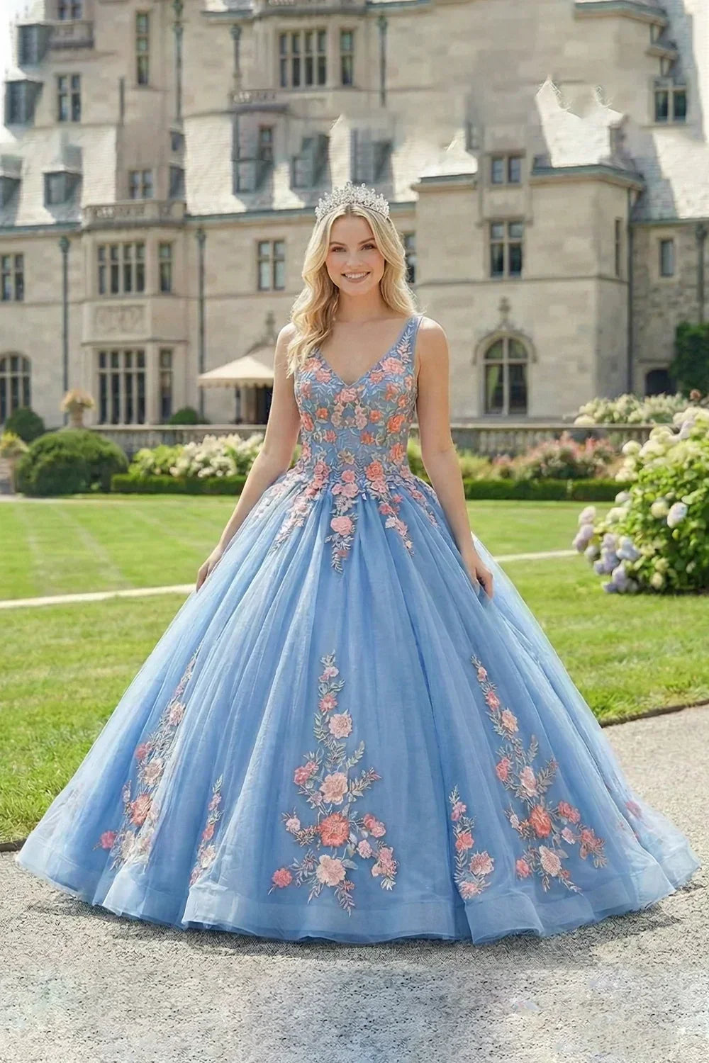 Woman in a blue ball gown with 3D floral lace, spaghetti straps, and a tiara outdoors