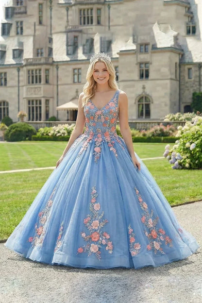 Woman in a blue ball gown with 3D floral lace, spaghetti straps, and a tiara outdoors