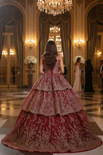Woman in layered red and gold ball gown with floral appliqué at elegant ballroom event