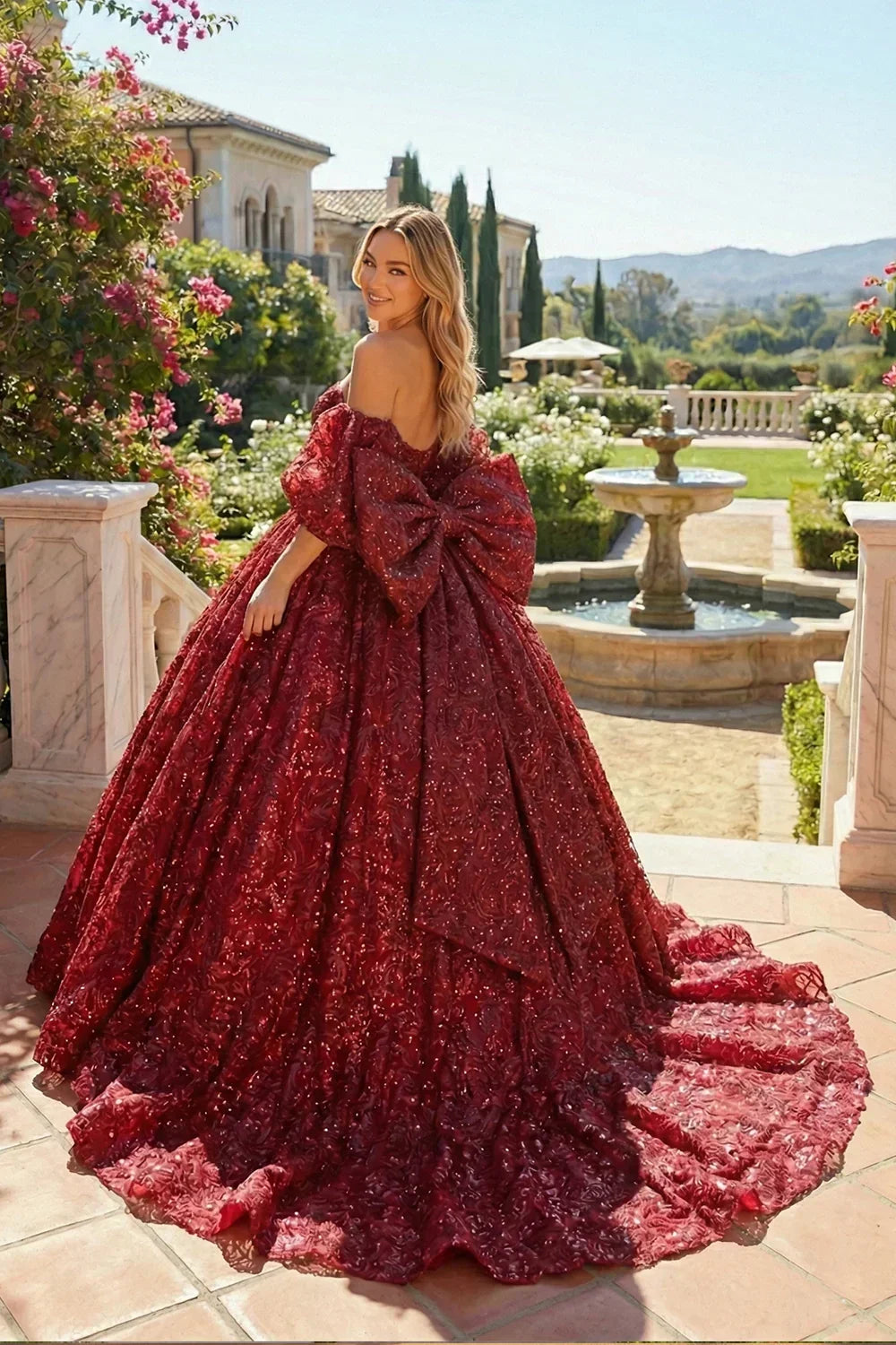 Woman in a red embroidered ball gown with a large bow, standing in a garden setting