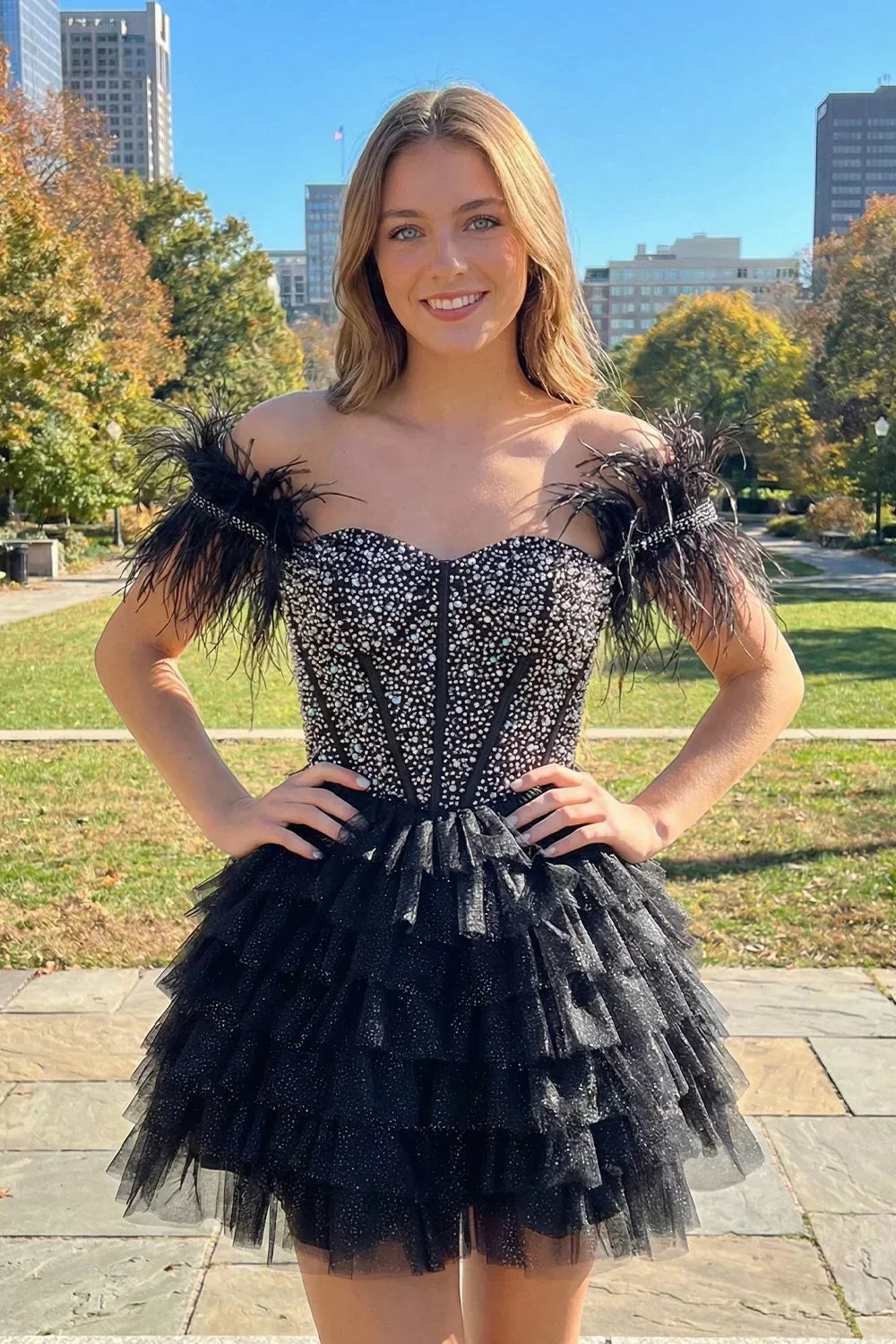 Woman in a black off-the-shoulder beaded homecoming dress with feathers and tiered tulle skirt