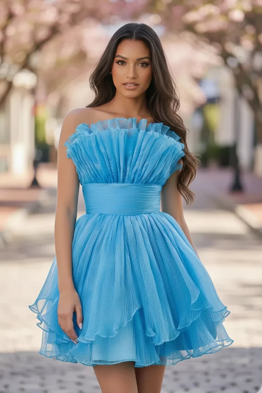 Woman wearing a blue strapless pleated A-line tiered short homecoming dress outdoors