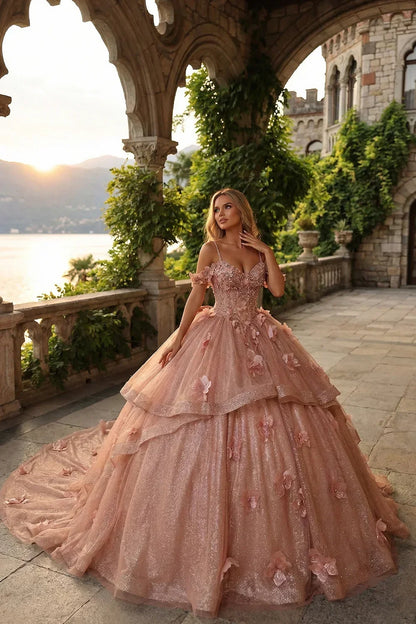 Rose gold ball gown with V-neck, ruffled tulle, and floral appliques in a castle garden