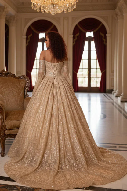 Woman in a glittery gold ball gown with cold shoulders and sheer sleeves in an elegant hall