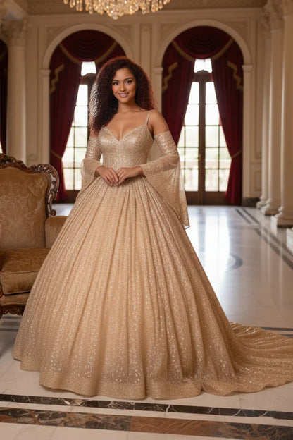 Woman in glittery champagne ball gown with cold shoulder sheer sleeves in an elegant hall