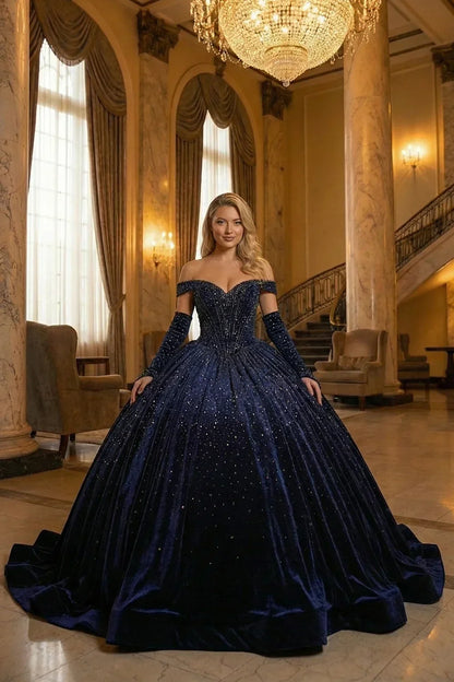 Woman in a luxurious navy blue velvet off-shoulder ball gown with glitter details in an elegant hall.