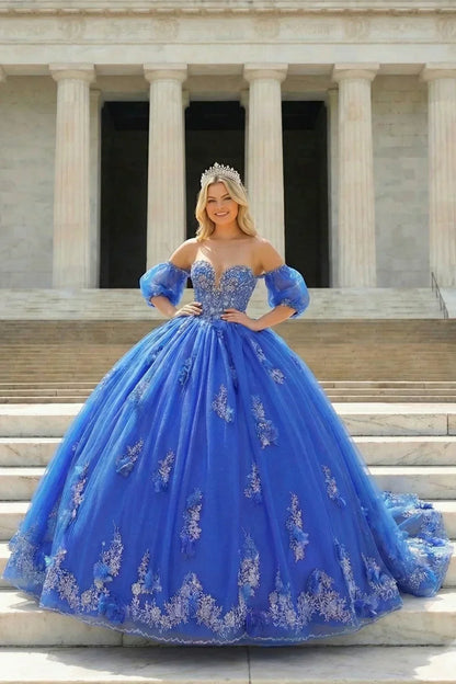Woman in off-shoulder royal blue ball gown with silver floral embroidery and tiara on stone steps