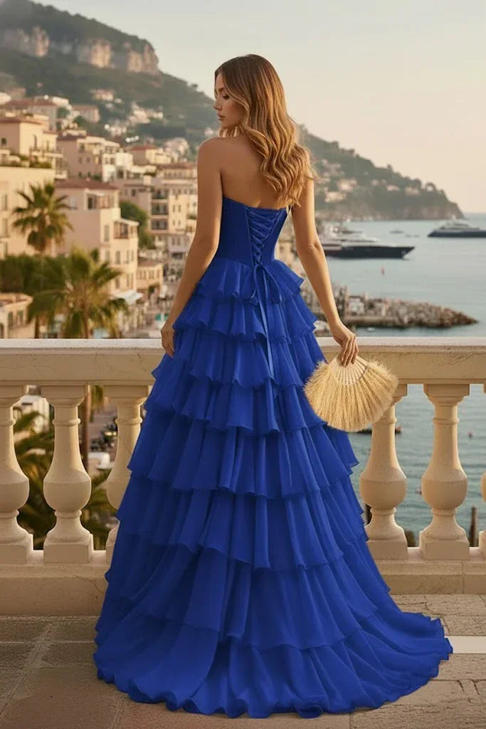 Woman in blue tiered ruffle corset prom dress with lace-up back on seaside balcony