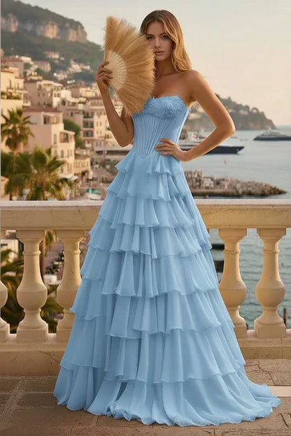 Woman in light blue tiered ruffle corset prom dress on balcony with scenic coastal view