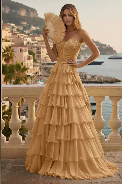 Woman in gold tiered ruffle corset prom dress with lace-up back, posing on a scenic terrace.