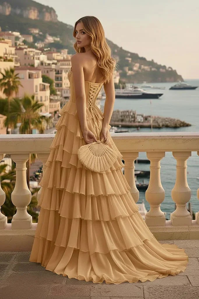 Woman in strapless tiered ruffle corset prom dress with lace-up back on balcony by waterfront