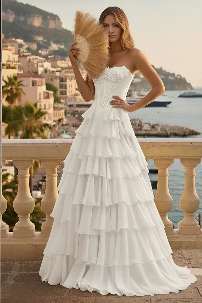 White tiered ruffle corset A-line prom dress with lace-up back, worn outdoors by the sea