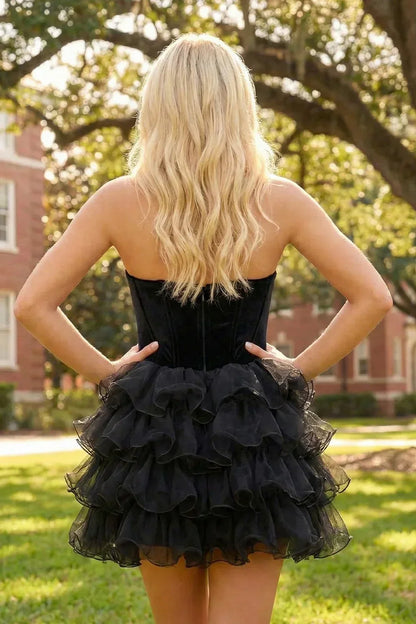 Woman in strapless black velvet ruffle short homecoming dress outdoors